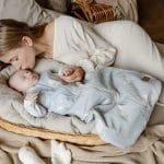 Mother kissing a baby in the sage green Happy Goose Olive sleeping bag