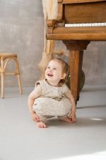 Laughing girl in the Herbs sleeping bag with legs crouching on the floor by a piano