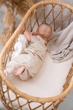 Niemowlę w śpiworku Herbs obraca się na bok w koszu, widok od tyłu z naszywką