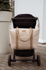XL Velvet stroller bag in warm beige hanging on the stroller handlebar