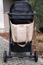 M Velvet stroller bag in warm beige hanging on the pram handlebar