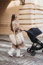 Mother pushing a stroller with the quilted XL Velvet bag in warm beige