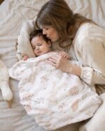 Mother kissing a baby covered with the Bunny cotton blanket with a bunny print