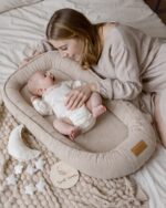 Mother cuddling a baby lying in the Velvet baby nest in cappuccino