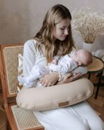 Mother holding a sleeping newborn on the Velvet nursing pillow in cappuccino
