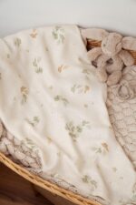 Eucalyptus bamboo muslin with a eucalyptus leaf print in a basket with a plush bunny