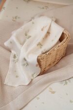 Eucalyptus bamboo muslin cloth with green sprigs draped over a wicker basket