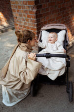 Mother crouching by a stroller with a baby under the Meri merino blanket in warm beige