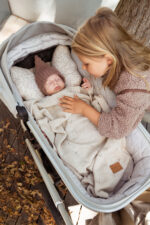 Little girl watching a baby in a pram covered with the Meri merino blanket in warm beige