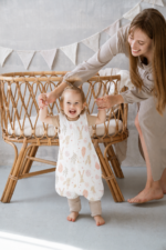 Mother holding the hands of a toddler girl walking in the Bunny sleeping bag with legs